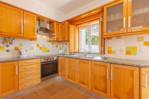 a kitchen with wooden cabinets and a window at Retiro do Livro in Óbidos