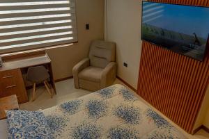 a bedroom with a bed and a chair and a flat screen tv at Casita Vera Style in Tarija
