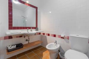 a bathroom with a toilet and a sink and a mirror at Retiro do Livro in Óbidos +18 photos
