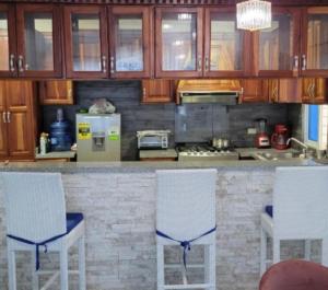 a kitchen with white chairs and a counter with a stove at Casa Same Hotel in Atacames