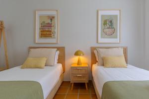 a bedroom with two beds and a lamp on a night stand at Retiro do Livro in Óbidos