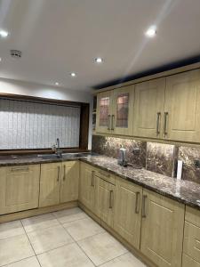 a kitchen with wooden cabinets and granite counter tops at Plus Properties Leeds 3 in Bradford +6 photos