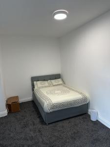 a bed in a room with a white wall at Plus Properties Leeds 3 in Bradford