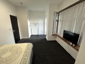 a bedroom with a bed and a flat screen tv at Plus Properties Leeds 3 in Bradford
