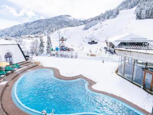 a resort with a swimming pool in the snow at Sauna Chalet Ahorn in Bad Kleinkirchheim