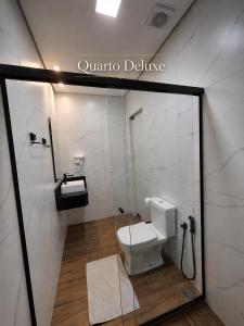a white bathroom with a toilet and a shower at Hotel Serra do Mar in Paranaguá