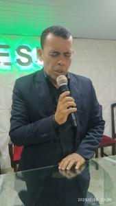 a man in a suit speaking into a microphone at Borges in Cabo de Santo Agostinho