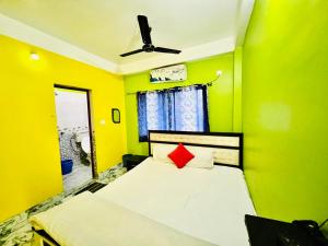 a yellow bedroom with a bed with a red pillow at Radha Rani lodge in Siliguri +28 photos