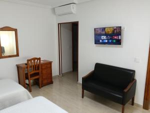 a bedroom with a chair and a bed and a desk at Hotel Mesón el 21 in Almería