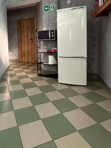 a kitchen with a refrigerator and a tiled floor at Noclegi Flauta in Mielno