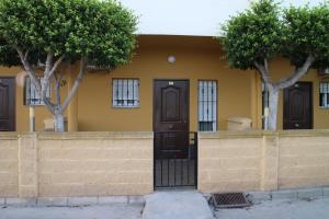 a yellow house with a black door and two trees at Hotel Mesón el 21 in Almería