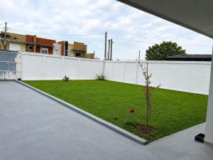a backyard with a white fence and a green yard at Casa Stepien ,Spacious House up to 11 guests in Fazenda Rio Grande Paraná Brazil in Fazenda Rio Grande