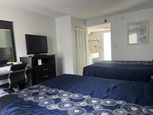 a bedroom with two beds and a desk and a television at Anastasia Inn - Saint Augustine in St. Augustine