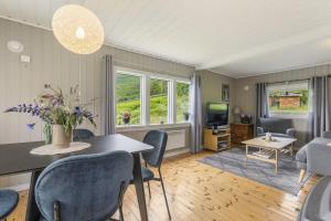 a living room with a table and chairs and a television at Kvila in Surnadal