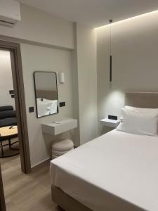 ein Schlafzimmer mit einem weißen Bett und einem Spiegel in der Unterkunft GreDa in Malia