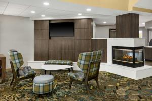 a lobby with a fireplace and two chairs and a tv at Residence Inn by Marriott Flint Grand Blanc in Flint