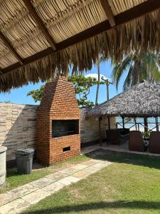 a brick oven in a patio with a straw roof at 204 Eco Paradise Cumbuco in Caucaia