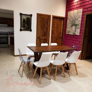 a dining room with a wooden table and white chairs at Un pequeño paraíso en Malinalco in Malinalco
