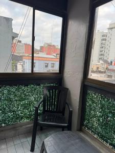 a chair sitting in a room with two windows at Danella in San Miguel de Tucumán
