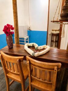 a wooden table with two chairs and a vase with flowers at Refúgio mar aberto BA in Alcobaça