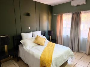 a bedroom with a bed with a yellow pillow on it at Postmasburg hotel in Postmasburg +10 photos