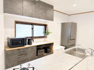 a kitchen with a sink and a tv on a counter at Tokyo Grand House in Akishima