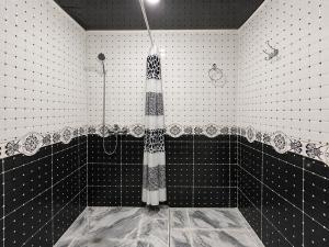 a bathroom with a shower with black and white tiles at Muso guesthouse in Yukary-Ukhum