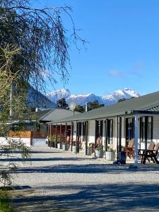 a building with snow covered mountains in the background at Heritage Park Lodge in Haast