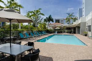 a pool with tables and chairs and an umbrella at TownePlace Suites by Marriott Boynton Beach in Boynton Beach