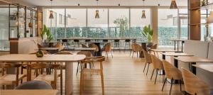 a restaurant with wooden tables and chairs and windows at B&B HOTEL Lisboa Aeroporto in Lisbon