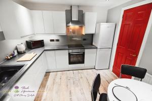a kitchen with white appliances and a red door at Thistle Apartments - Marischal Square in Aberdeen