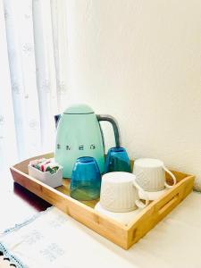 a tea kettle and cups on a wooden tray at DomoMea Rooms in Loculi