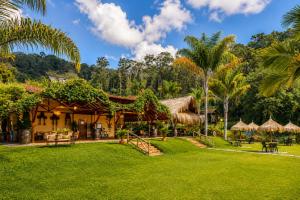 a resort with a green lawn and palm trees at Hotel Pietrasanta Cabañas frente a la Represa Peñol Guatape in Guatapé