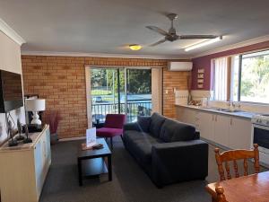 a living room with a couch and a kitchen at Beachlander Self-Contained Holiday Apartments in Coffs Harbour