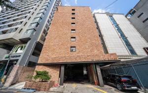 a tall brick building with a car parked in front of it at H hotel Gasan in Seoul