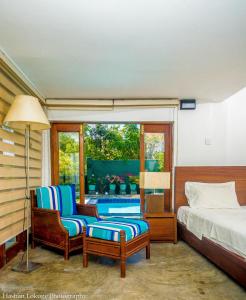 a bedroom with two chairs and a bed and a window at serendipty lake villa in Panadura