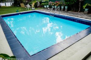 a swimming pool with blue tiles in a yard at serendipty lake villa in Panadura +2 photos