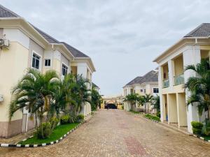 a road between two houses with palm trees on the sides at Crispan Luxury Apartment in Jos