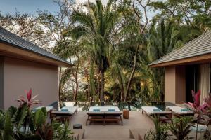 a resort patio with tables and chairs and palm trees at One&Only Mandarina in Lo de Marcos