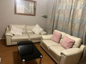 a living room with two couches and a table at 2 bedroom house  +1 photo