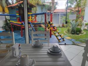 a table with chairs and a playground in a yard at LM Suítes in Búzios