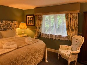 a bedroom with a bed and a chair and a window at Corriegour Lodge Hotel in Spean Bridge