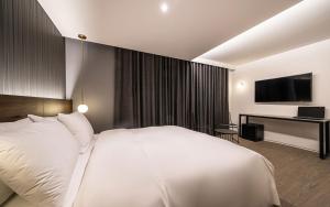 a bedroom with a large white bed and a desk at H hotel Gasan in Seoul