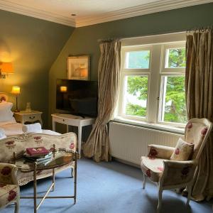 a bedroom with a bed and a tv and a window at Corriegour Lodge Hotel in Spean Bridge