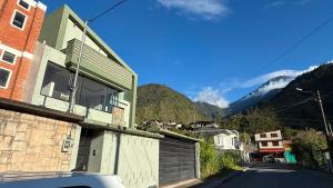 a house on a street with mountains in the background at Volcán Suits in Baños