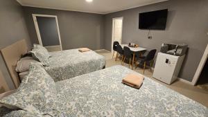a bedroom with two beds and a table with a television at Hostal HDQ en Concepción Sector Collao in Concepción +3 photos