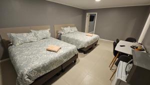 a small room with two beds and a table and a tableablish at Hostal HDQ en Concepción Sector Collao in Concepción