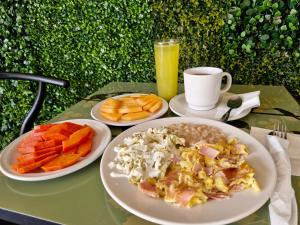 ein Tisch mit Tellern voller Essen und einem Glas Orangensaft in der Unterkunft Hotel Alcazar - Guadalajara Centro Historico in Guadalajara