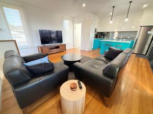 a living room with two leather couches and a table at Loveday on Landsborough in South West Rocks