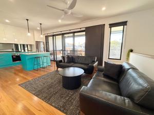 a living room with a leather couch and a table at Loveday on Landsborough in South West Rocks